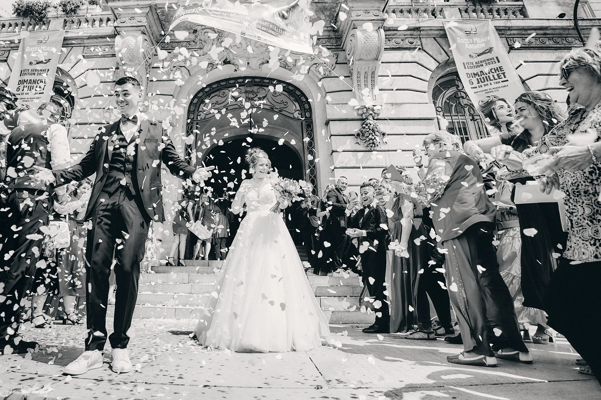 Sortie de mairie des mariés sous une pluie de confettis, en noir et blanc